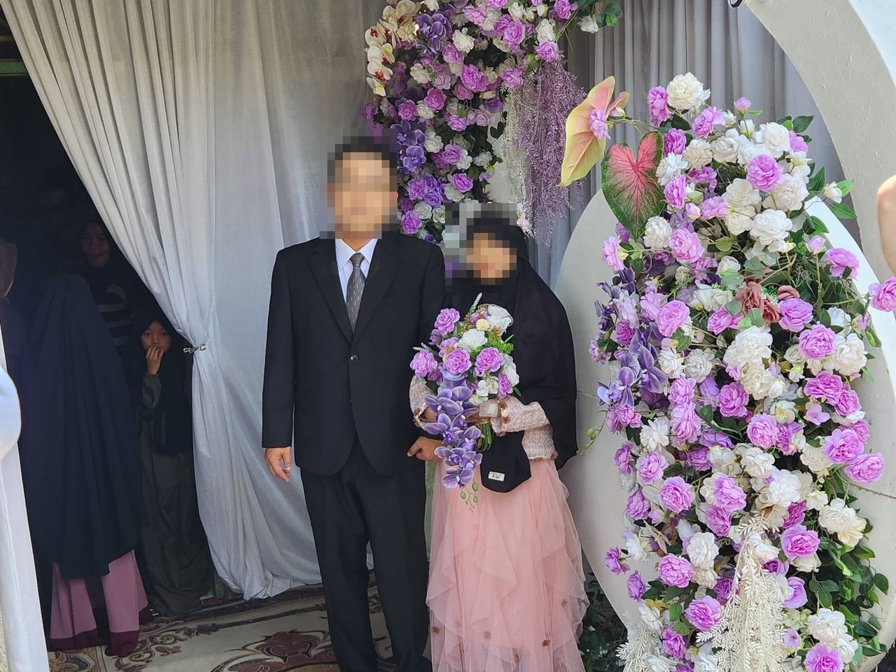 꽃 아치 앞에 나란히 선 신랑 신부